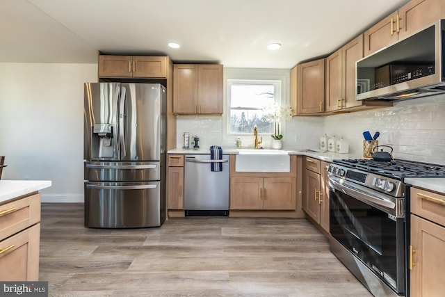 kitchen with sink, backsplash, stainless steel appliances, and light wood-type flooring