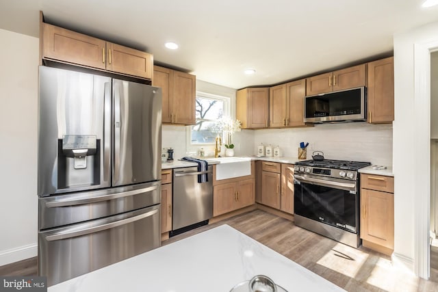 kitchen with sink, decorative backsplash, stainless steel appliances, and light hardwood / wood-style floors