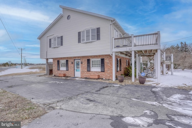 view of front of house featuring brick siding, stairway, and a wooden deck