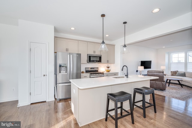 kitchen featuring a kitchen island with sink, sink, gray cabinets, and stainless steel appliances