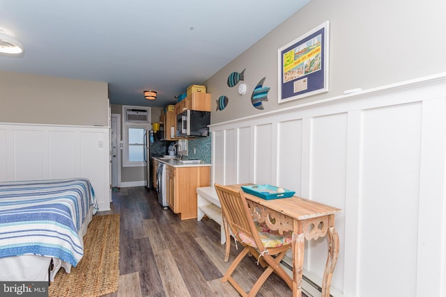 kitchen with an AC wall unit, light brown cabinetry, backsplash, dark hardwood / wood-style flooring, and stainless steel appliances