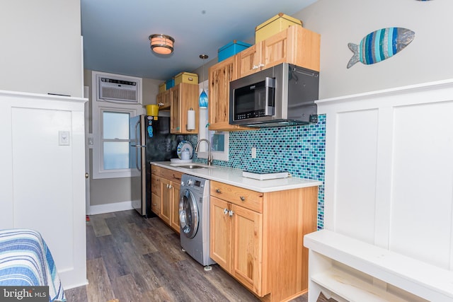 kitchen featuring appliances with stainless steel finishes, a wall mounted air conditioner, washer / clothes dryer, tasteful backsplash, and sink