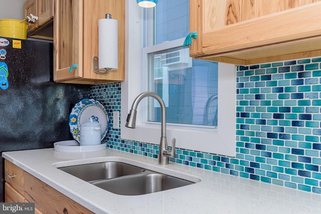 kitchen with light stone countertops, sink, and decorative backsplash