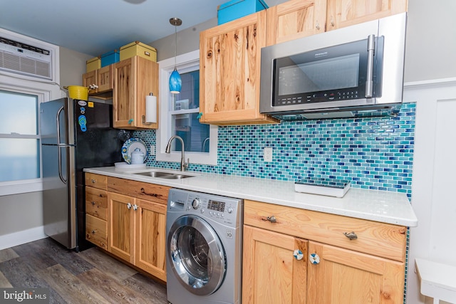 kitchen featuring washer / dryer, sink, tasteful backsplash, decorative light fixtures, and stainless steel appliances