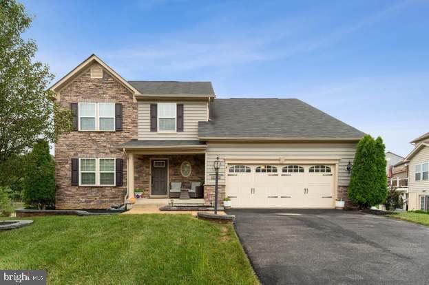 view of front of home featuring an attached garage, aphalt driveway, and a front yard