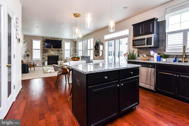 kitchen featuring a center island, decorative light fixtures, appliances with stainless steel finishes, open floor plan, and a sink