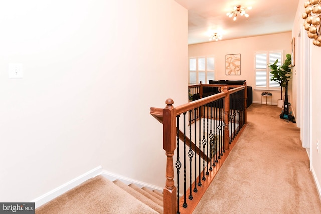 corridor featuring light carpet, baseboards, and an upstairs landing