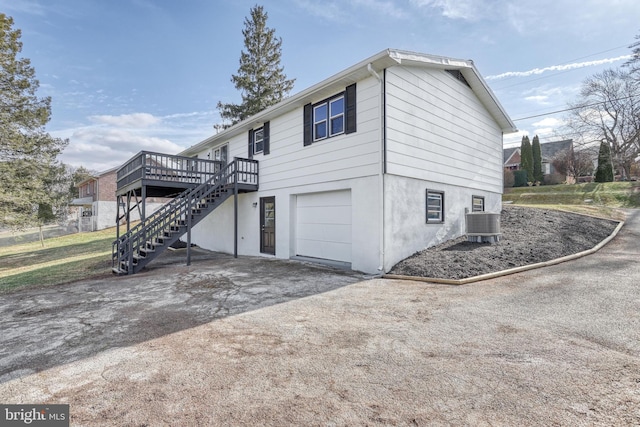 view of property exterior featuring a garage, a deck, and central air condition unit