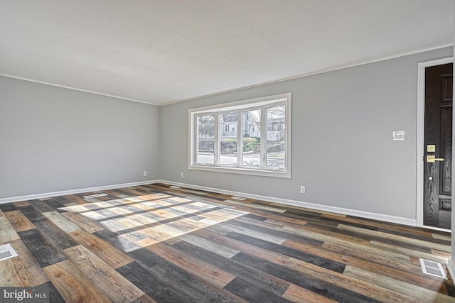 empty room featuring ornamental molding and dark wood-type flooring