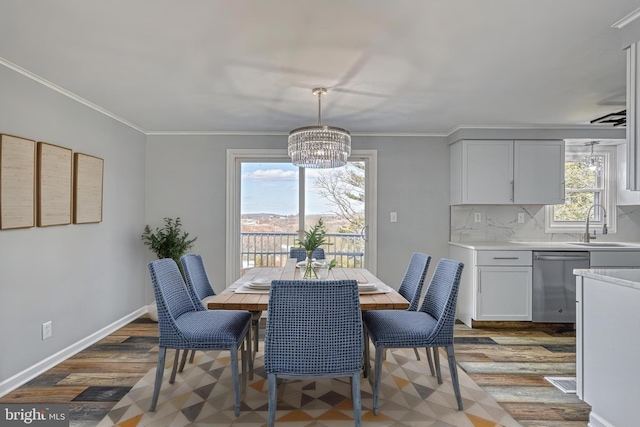 dining area featuring crown molding, sink, hardwood / wood-style floors, and a notable chandelier