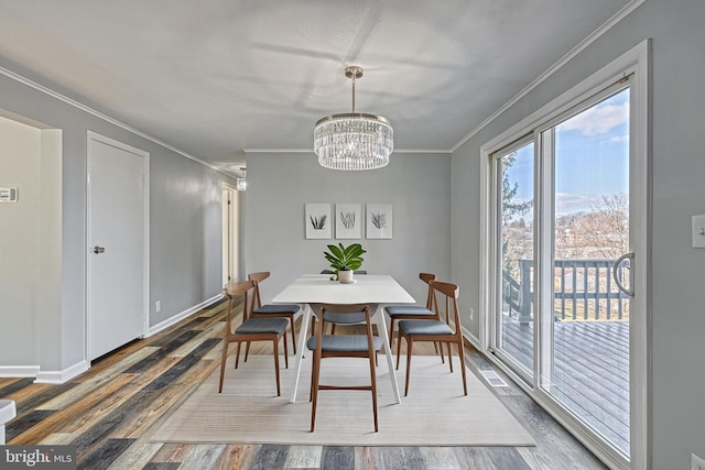 dining room featuring ornamental molding, wood-type flooring, and an inviting chandelier