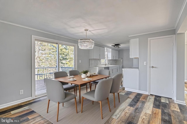 dining space with ornamental molding, dark hardwood / wood-style floors, sink, and a notable chandelier