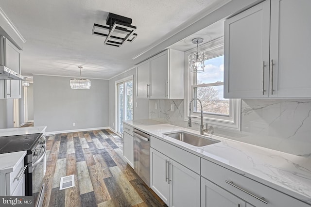 kitchen with stainless steel appliances, decorative light fixtures, sink, and a wealth of natural light