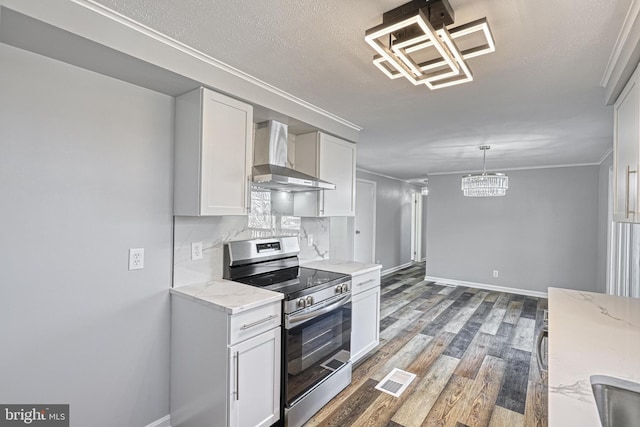 kitchen with white cabinets, hanging light fixtures, wall chimney range hood, and electric range