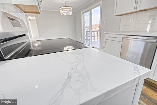 kitchen with pendant lighting, hardwood / wood-style flooring, stainless steel dishwasher, and white cabinets