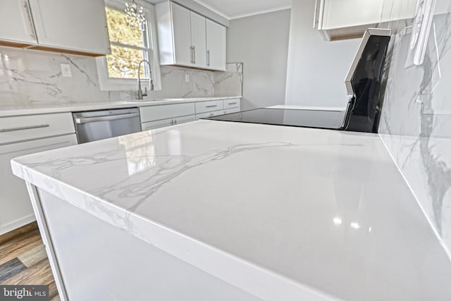 kitchen with sink, stainless steel dishwasher, white cabinets, hardwood / wood-style floors, and backsplash