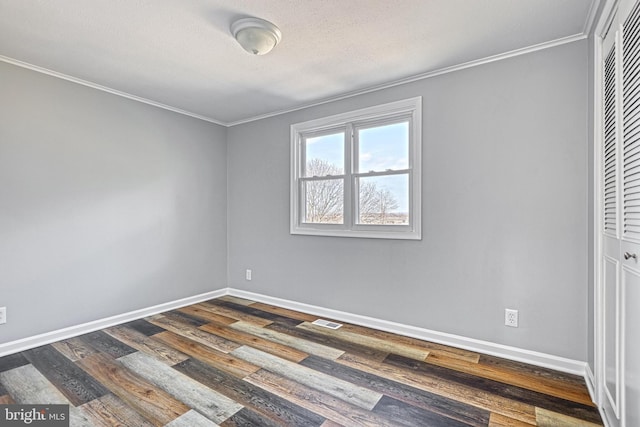 unfurnished room featuring dark wood-type flooring, crown molding, and a textured ceiling