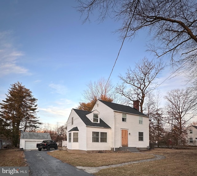 view of front facade featuring roof with shingles, a chimney, and an outdoor structure