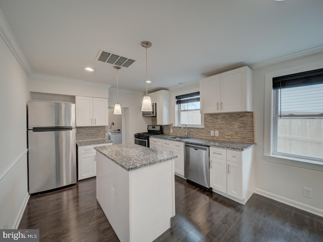 kitchen featuring sink, appliances with stainless steel finishes, white cabinetry, hanging light fixtures, and a center island