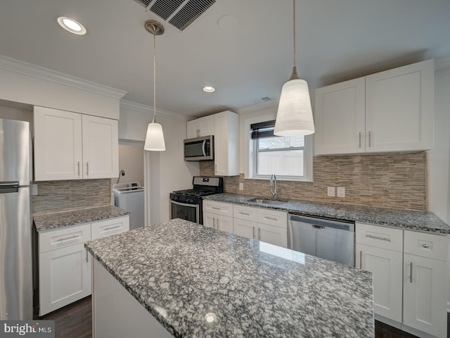 kitchen featuring washer / dryer, sink, white cabinetry, pendant lighting, and stainless steel appliances