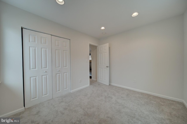 unfurnished bedroom featuring light carpet and a closet