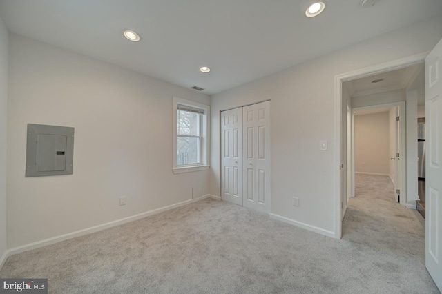 unfurnished bedroom featuring light carpet, electric panel, and a closet