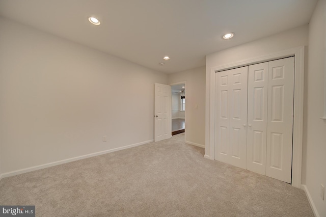 unfurnished bedroom with light colored carpet and a closet