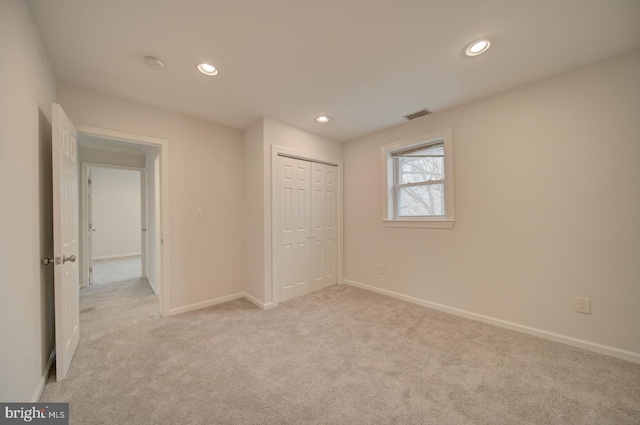 unfurnished bedroom with light colored carpet and a closet