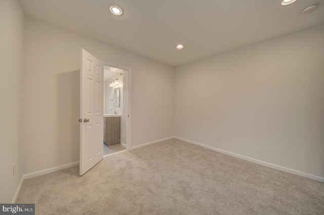 interior space with ensuite bathroom and light carpet