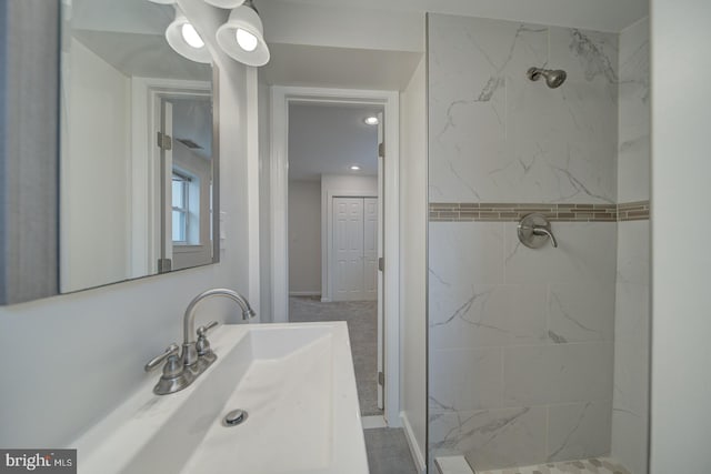 bathroom featuring tiled shower and sink