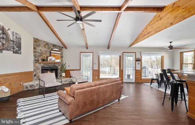 living room with a fireplace, wood walls, lofted ceiling with beams, ceiling fan, and dark wood-type flooring