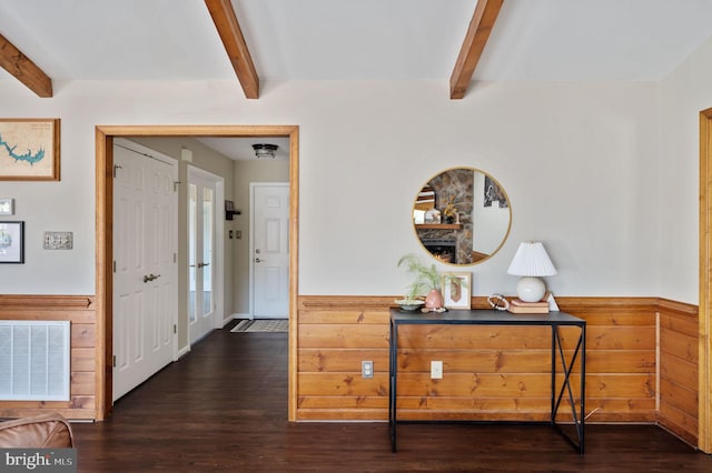 hallway with beamed ceiling, dark hardwood / wood-style floors, and wooden walls