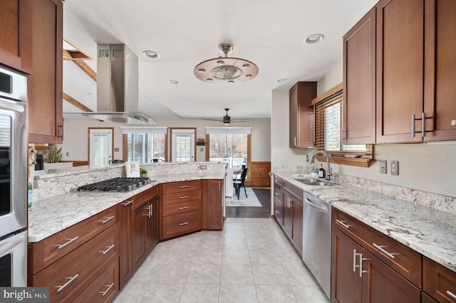 kitchen featuring sink, appliances with stainless steel finishes, kitchen peninsula, island exhaust hood, and light stone countertops