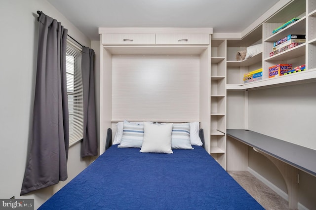 bedroom featuring built in desk and light carpet