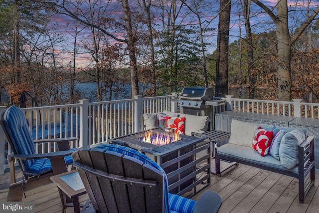 deck at dusk with area for grilling and an outdoor living space with a fire pit