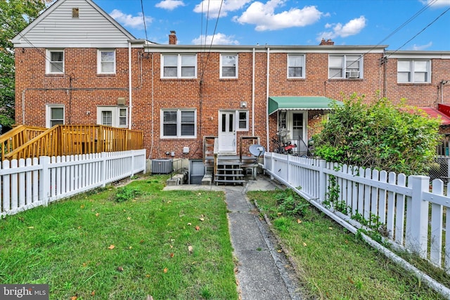 rear view of house featuring central AC and a lawn