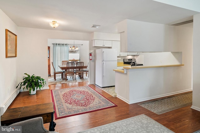 kitchen with white cabinetry, hardwood / wood-style flooring, white fridge, and electric range