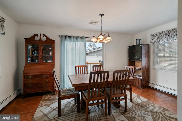 dining space with dark wood-type flooring, a notable chandelier, and baseboard heating