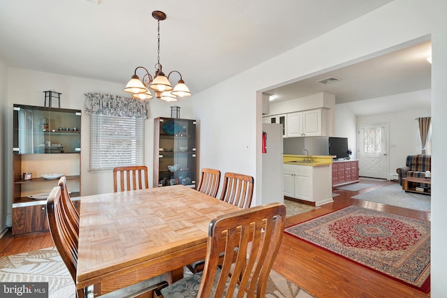 dining space featuring sink, an inviting chandelier, and light wood-type flooring