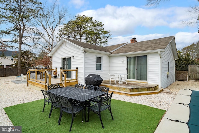 rear view of property with a wooden deck and a lawn