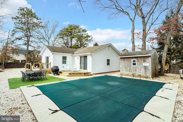 rear view of property featuring a pool side deck and a shed