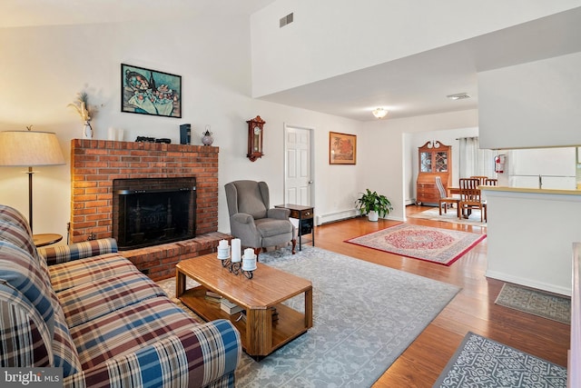 living room featuring a baseboard heating unit, hardwood / wood-style floors, and a fireplace