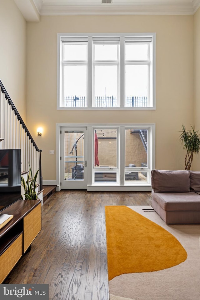 living room with crown molding, a towering ceiling, a wealth of natural light, and dark hardwood / wood-style flooring