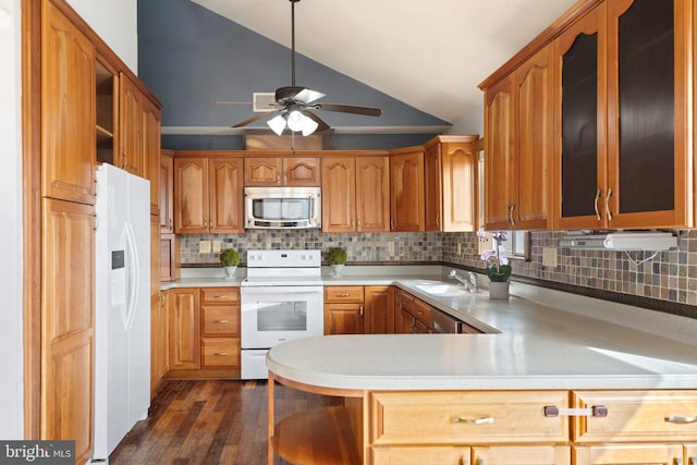 kitchen featuring sink, white appliances, dark wood-type flooring, vaulted ceiling, and kitchen peninsula