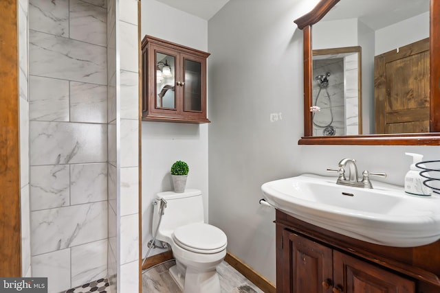 bathroom with tiled shower, vanity, and toilet