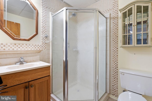 bathroom featuring walk in shower, vanity, toilet, and tile walls