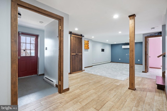 basement with light hardwood / wood-style floors, a barn door, and baseboard heating