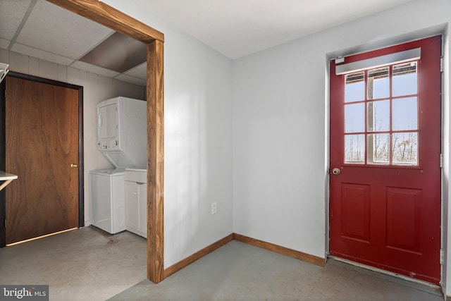 interior space featuring concrete flooring, stacked washer and clothes dryer, and a paneled ceiling