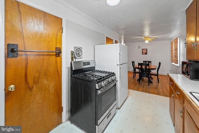 kitchen with ceiling fan, tile countertops, and stainless steel gas stove