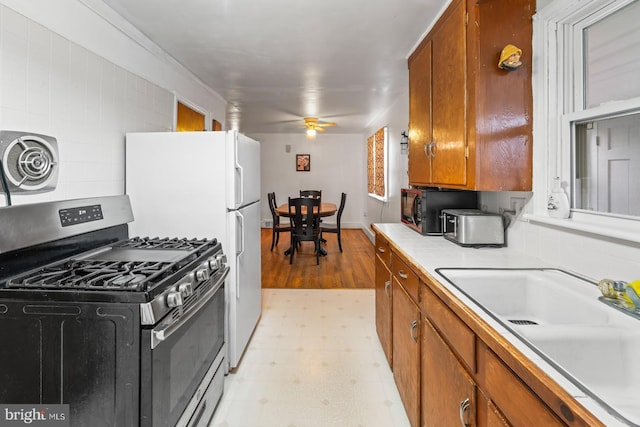 kitchen with ceiling fan, sink, gas range, and decorative backsplash